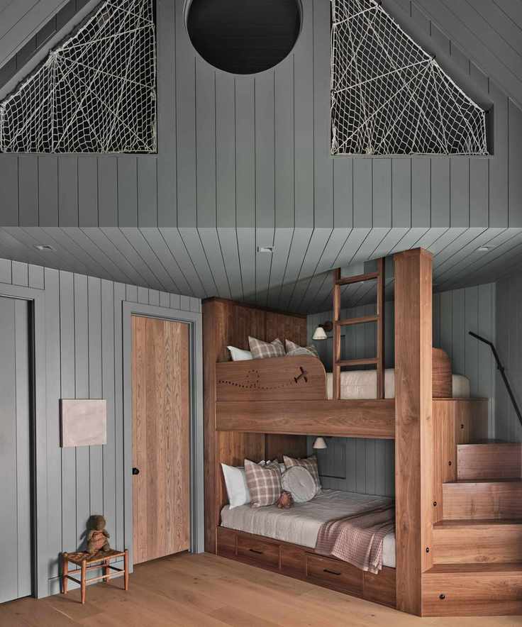 A children's bedroom with wall paneling painted mid-blue and wooden accents