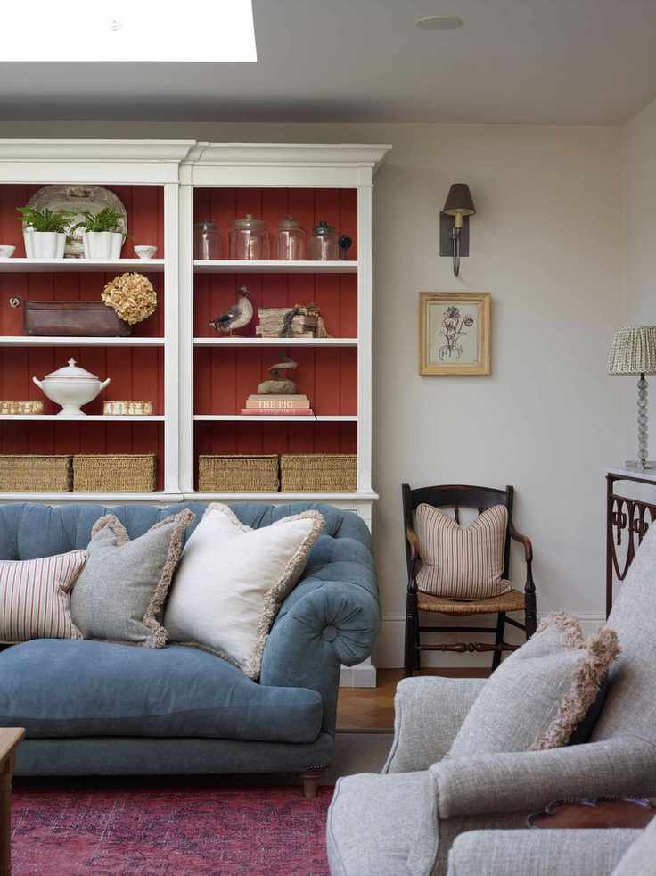 living room with blue sofa and grey armchair with red paneled white display shelving