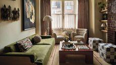 a Victorian style living room with bay window with two sheepskin chairs, a burgundy tile fireplace, green sofa and a wooden coffee table