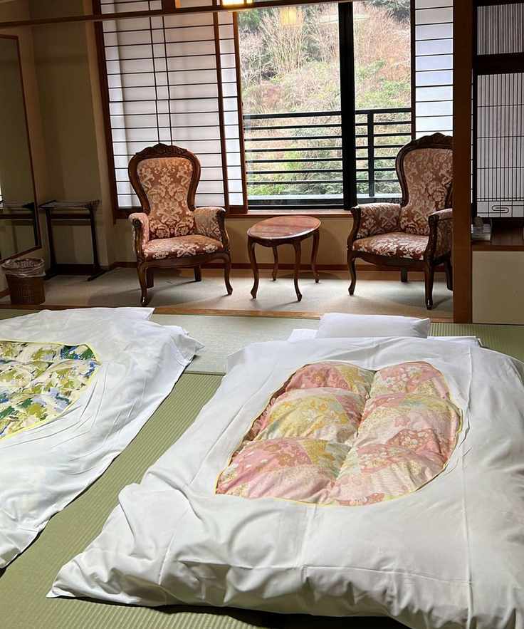 A traditional Japanese ryokan bedroom featuring futon beds on tatami mats
