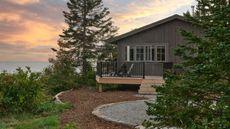 a small lakeside cabin with a wrap around porch, single firepit, and a view over the lake