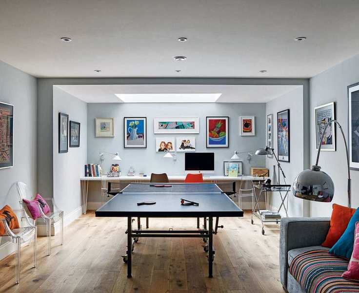 A large neutral kids playroom with table tennis table and colorful cushions and wall art.
