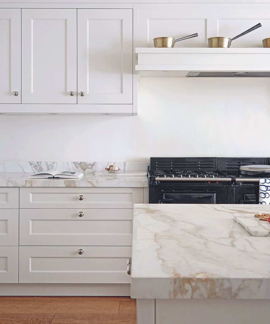 Kitchen with white units and wooden floor.