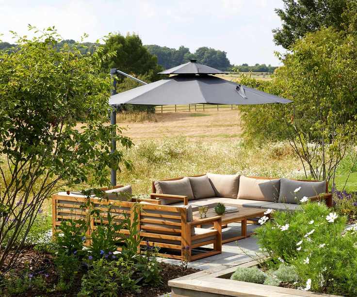 A cantilevered patio umbrella over outdoor furniture in a backyard in summer