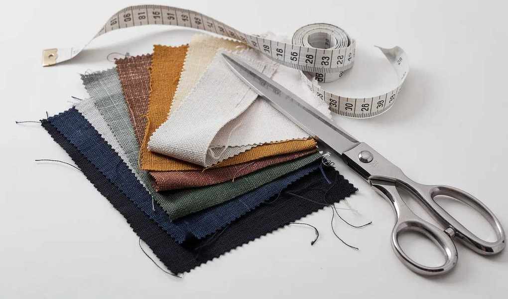 An assortment of beautiful fabric swatches in various colors, displayed next to a measuring tape and scissors, ideal for sewing and quilting projects.
