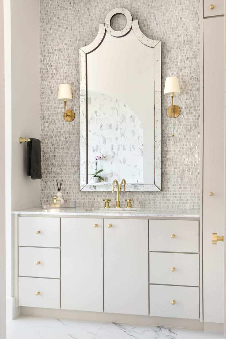 A large mirror with shimmering mosaic tiles over a cream and gold vanity
