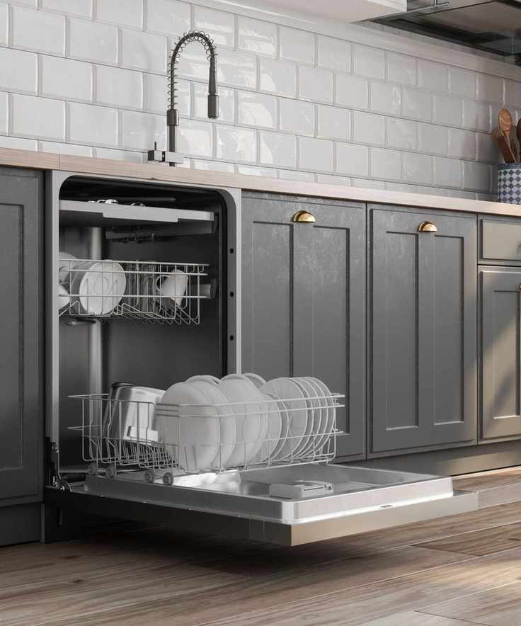 An open dishwasher integrated into grey kitchen cabinets next to a kitchen sink. White plates stacked in the trays.