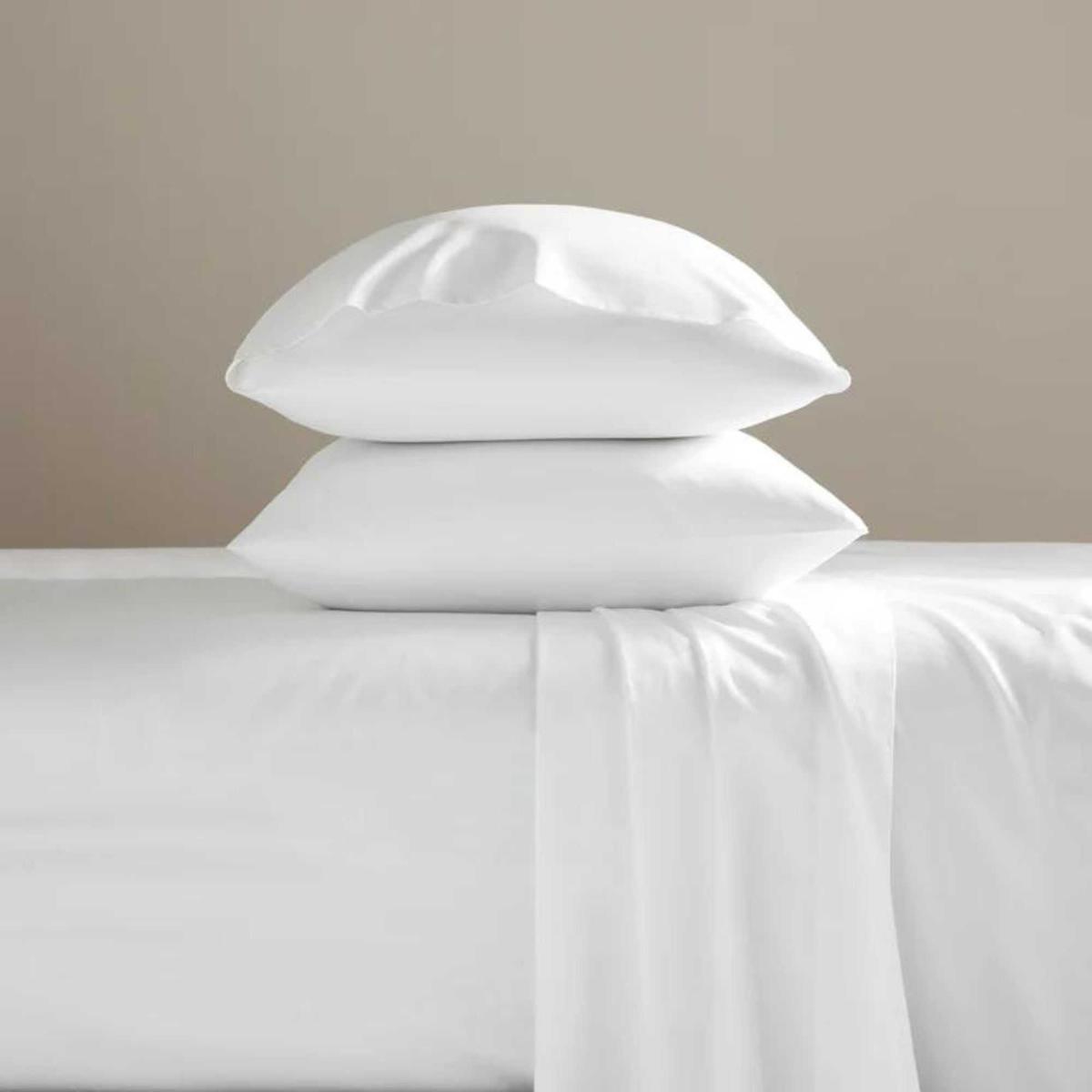 Brooklinen Classic Percale Core Sheet Set on a bed against a beige wall.