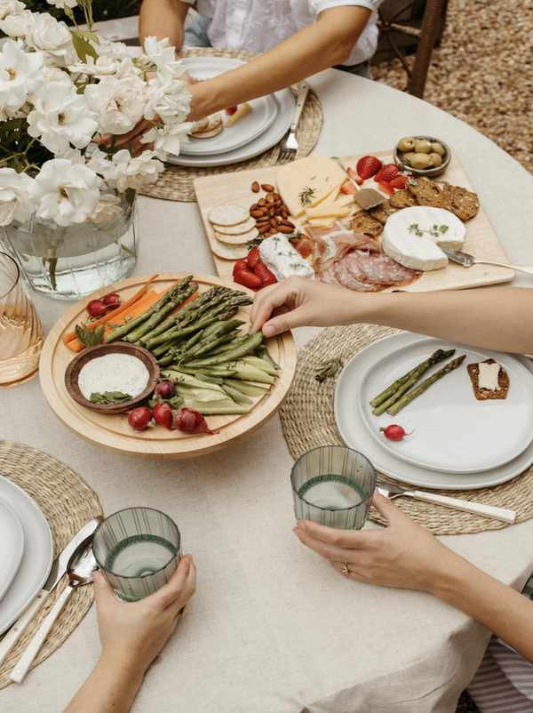 Women practicing mindful eating rituals at outdoor dining table.
