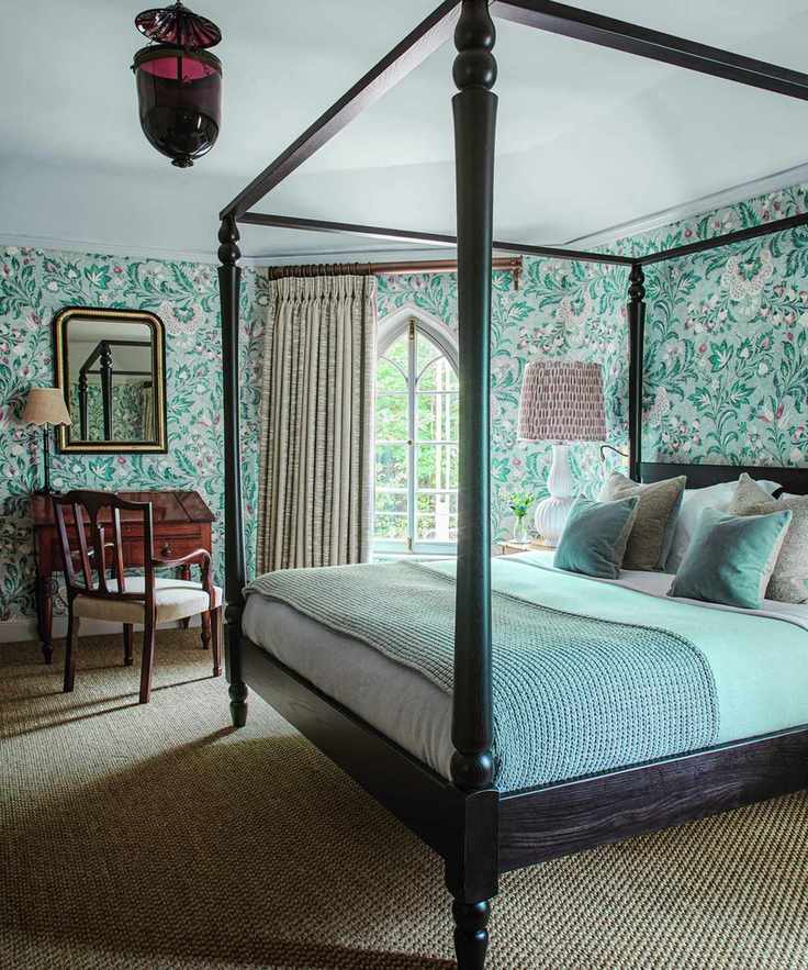bedroom with wooden four poster and patterned wallpaper