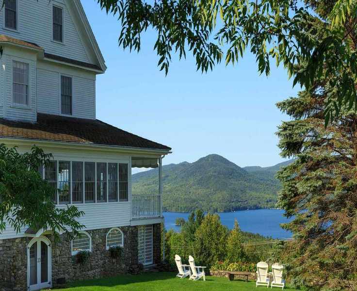 Cape cod home overlooking lake with Adirondack chairs in backyard