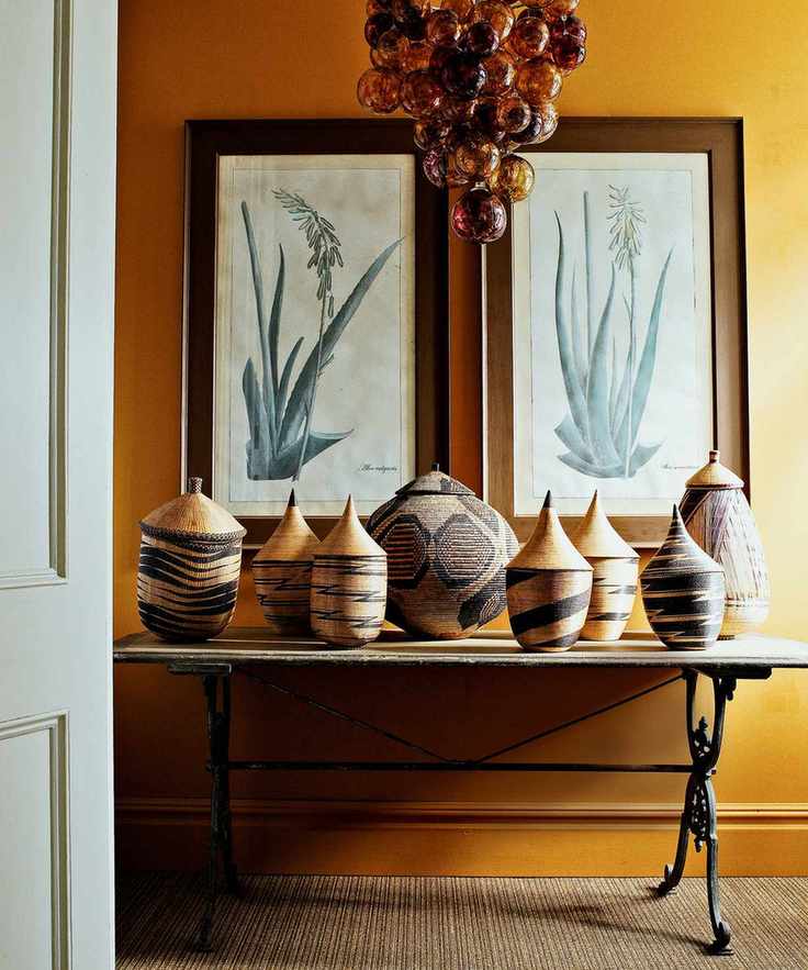 Entryway with yellow wallpaper, botanical art, and a collection of African baskets on a table.