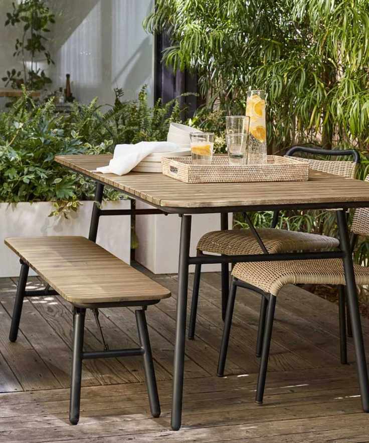 Outdoor table, bench and chairs in wood and black metal with living wall behind