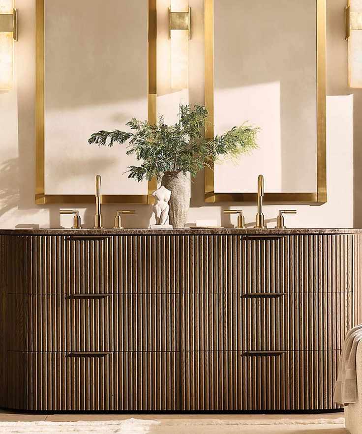 A neutral bathroom with a dark fluted wood vanity and gold mirrors