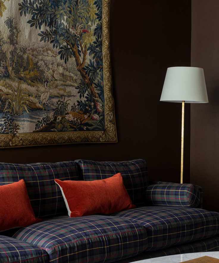 Study with dark walls and plaid sofa