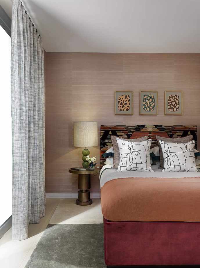 Pink wallpaper, red velvet bed base, orange throw