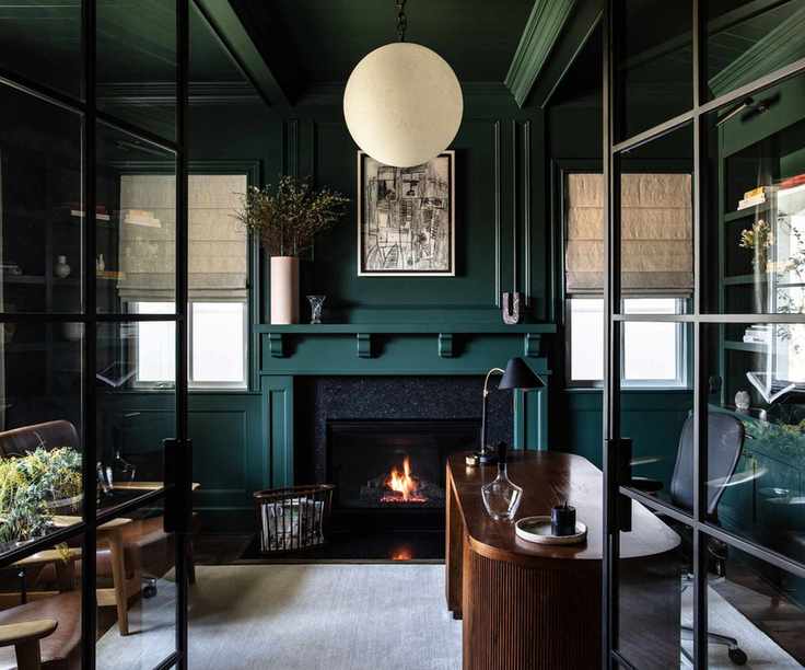 Home office painted in deep teal with dark wood furniture
