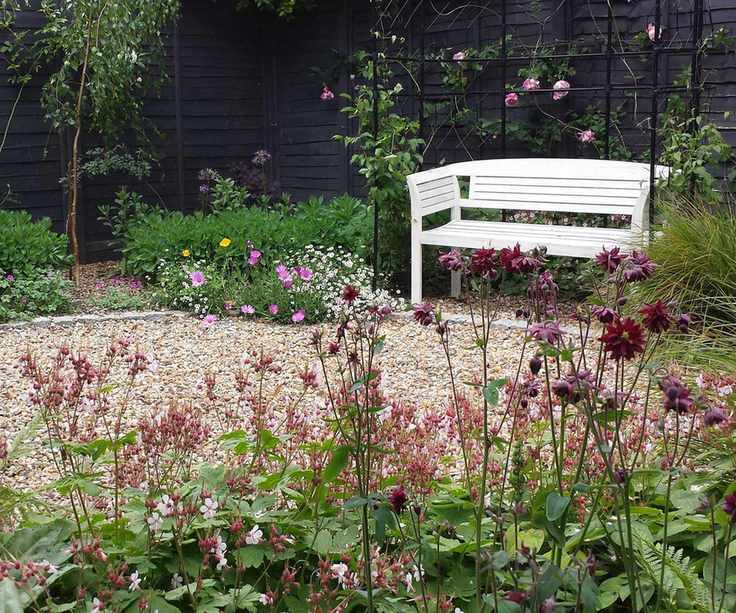 gravel patio with white bench surrounded by plants