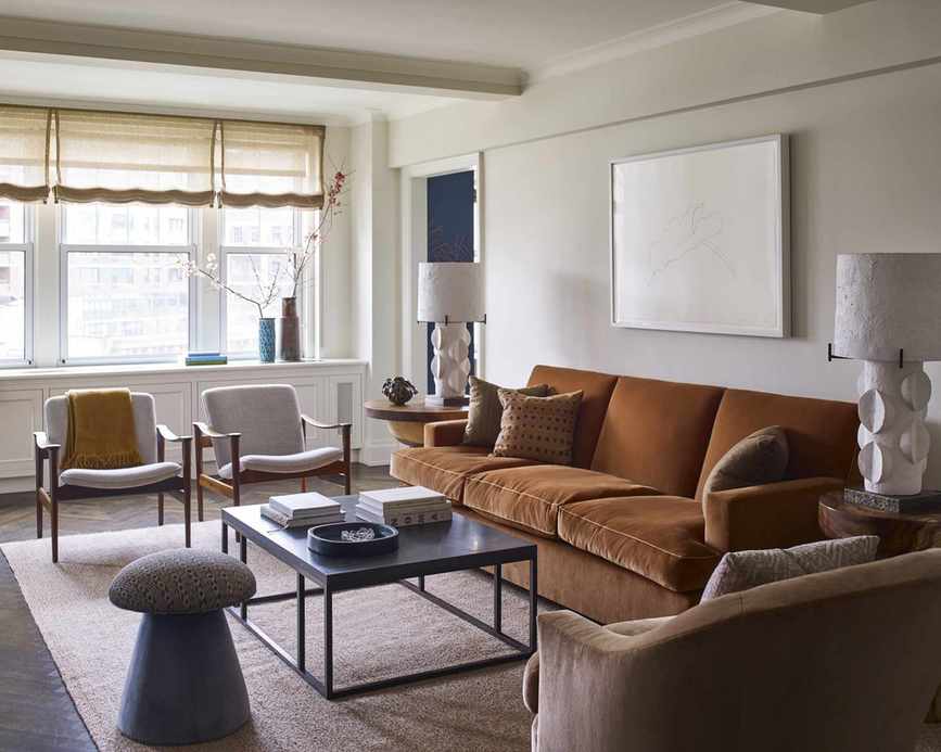 A living room with a brown sofa featuring velvet upholstery in a mid-century modern setting
