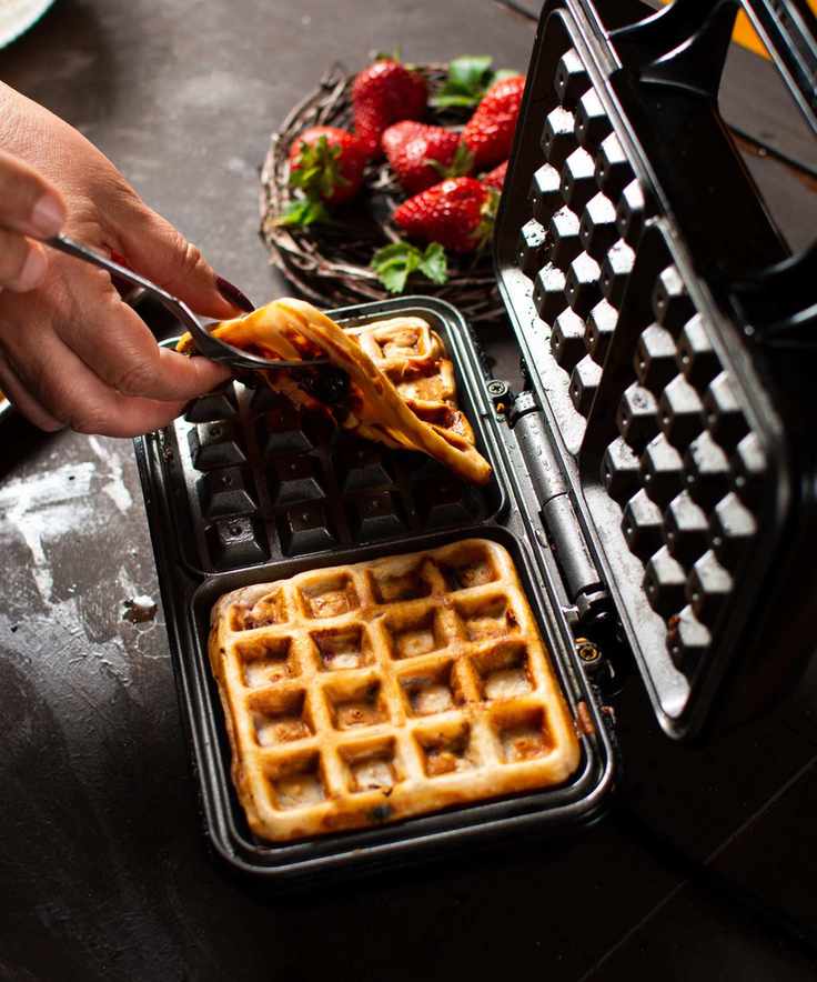 Lifting waffles out of a black, non-stick waffle maker