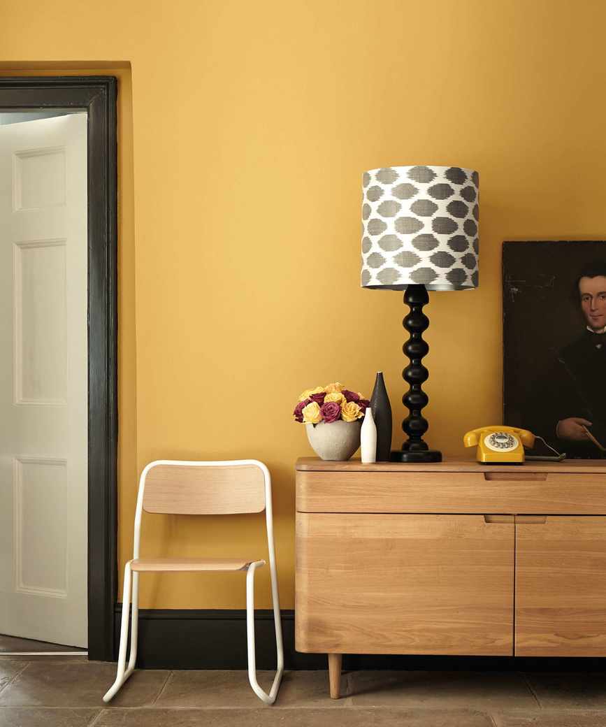 A yellow living room featuring a wooden sideboard next to a cozy chair