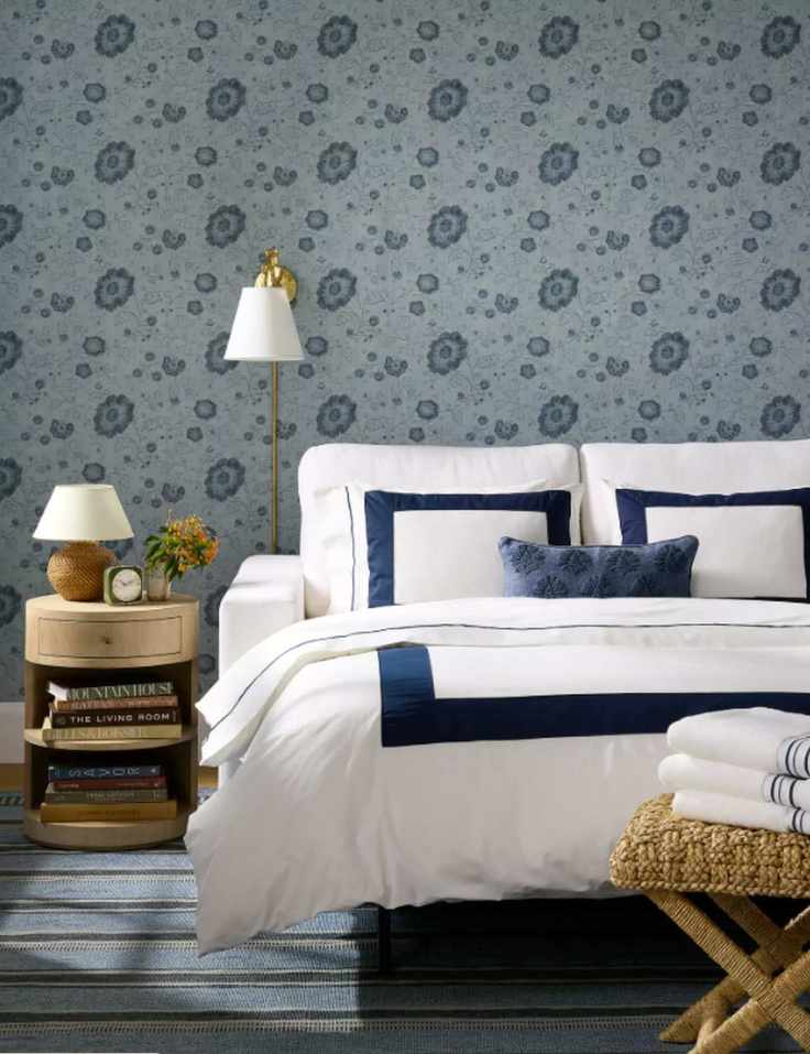 Serena & Lily white sleeper sofa styled for guests inside of a blue wallpapered bedroom