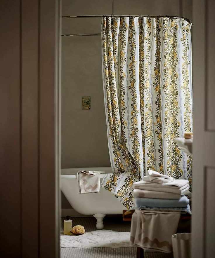Jungle-themed shower curtain from Anthropologie hanging from a rail suspended from the ceiling, over a clawfoot bath. Viewed through the bathroom doorway.