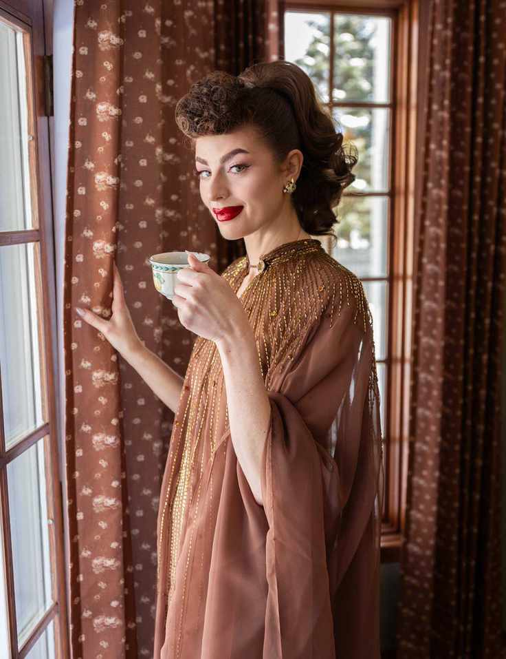 Ms. Maverick Muse in her childhood dining room with patterned curtains