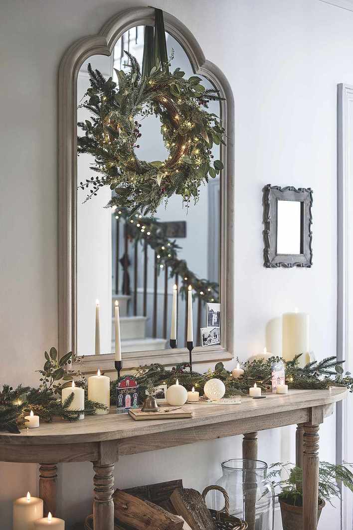 Hallway with Christmas wreath and console table adorned with foliage