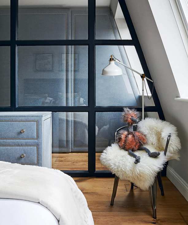 A glass partition wall dividing a narrow gray bedroom storage space.