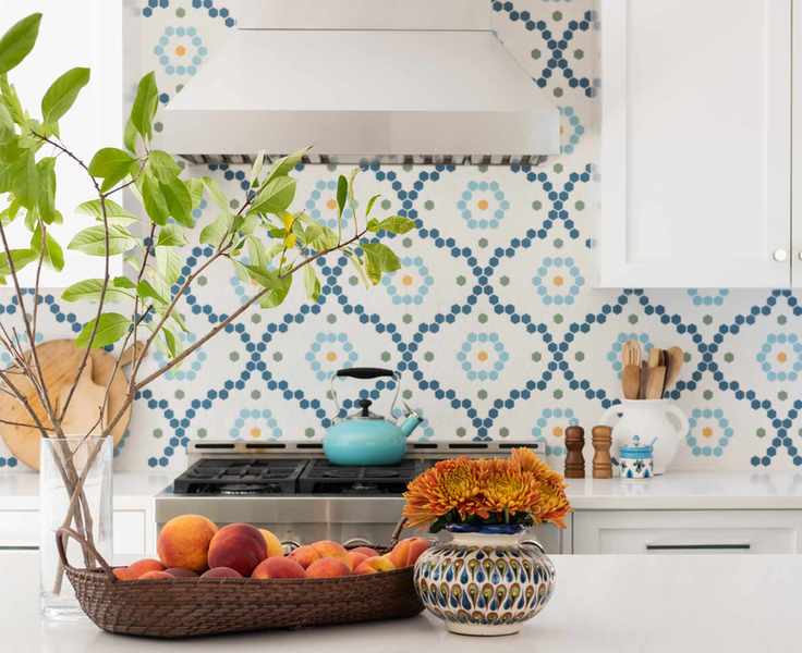 A white kitchen with blue island, and white and blue patterned tiles.
