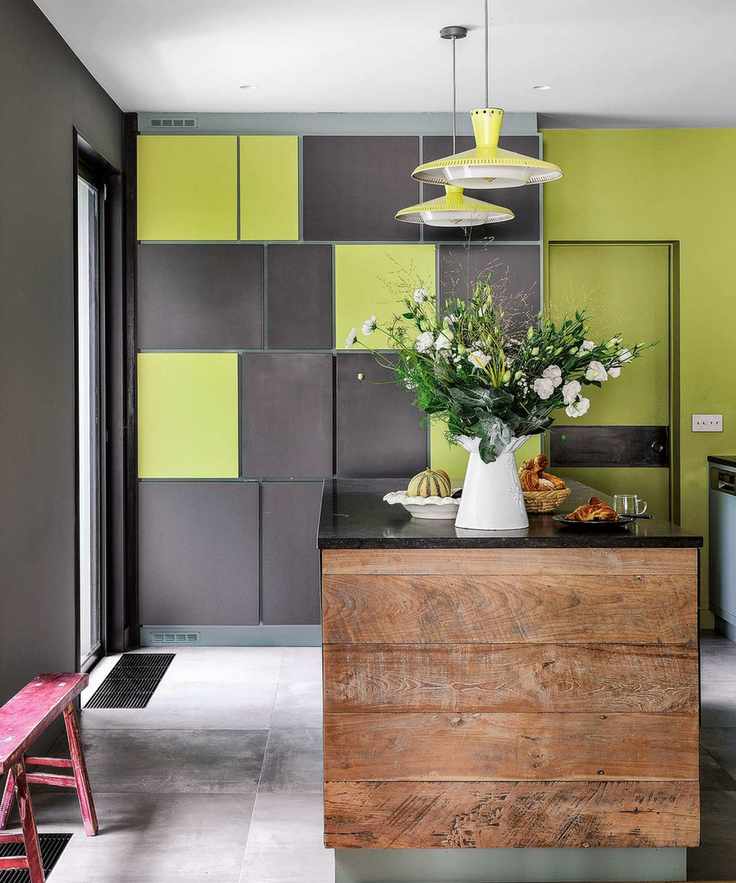 A dark grey kitchen with lime green wall and lighting accents and a wooden kitchen island.