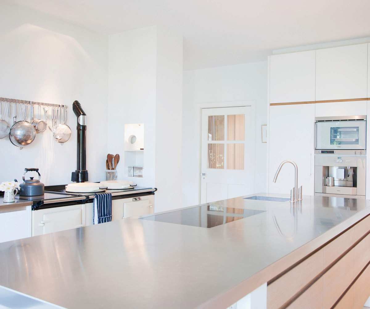 Modern kitchen with stainless steel counters, hanging pans and a classic style kettle on the stove