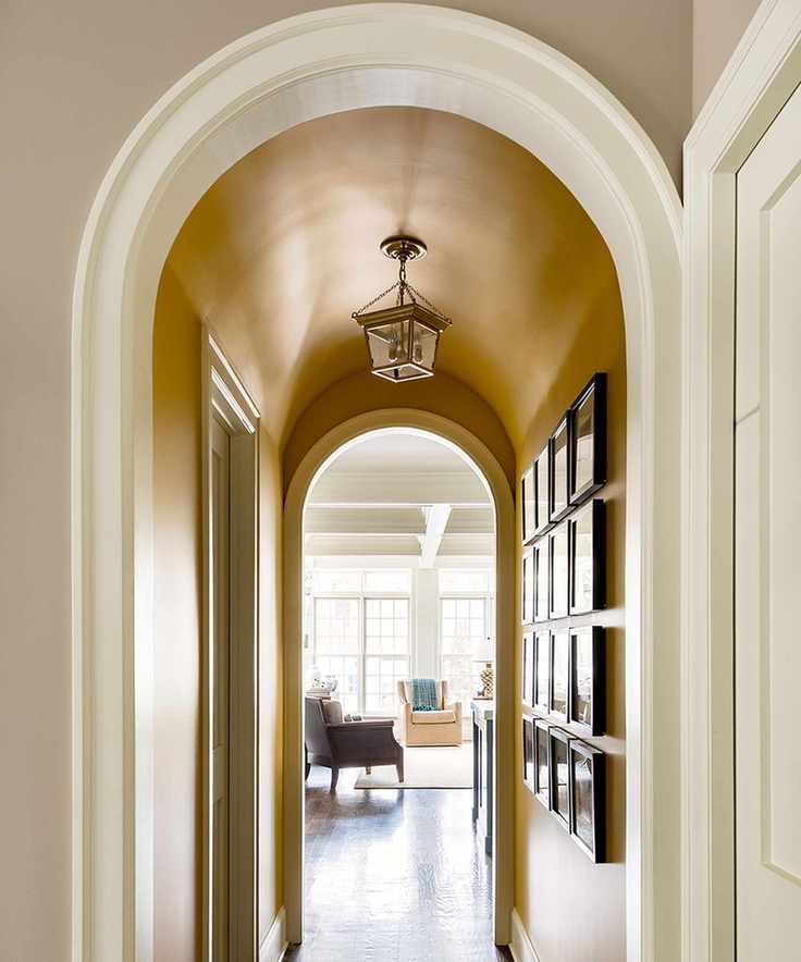 A yellow-painted small hallway with an archway to the living room and a gallery wall.