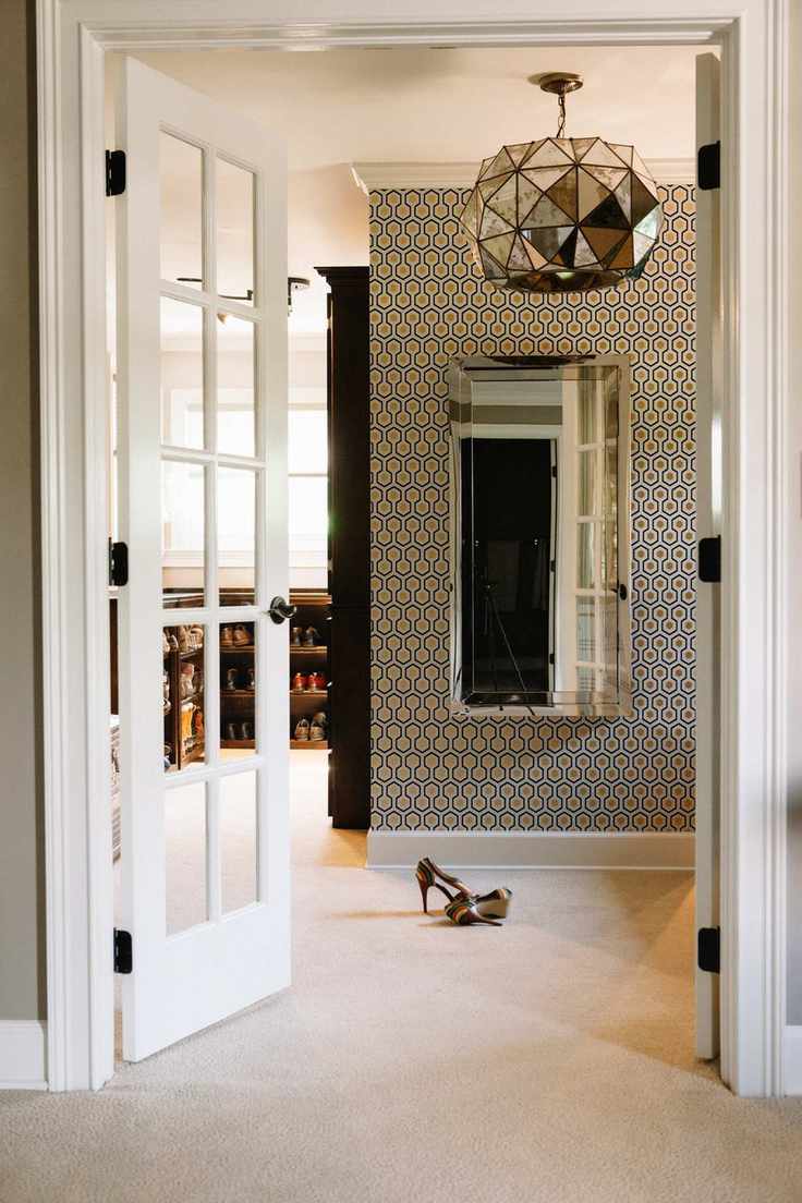 walk in closet with French style doors, wallpaper, shoes to one side, vintage silver pendant light, carpet