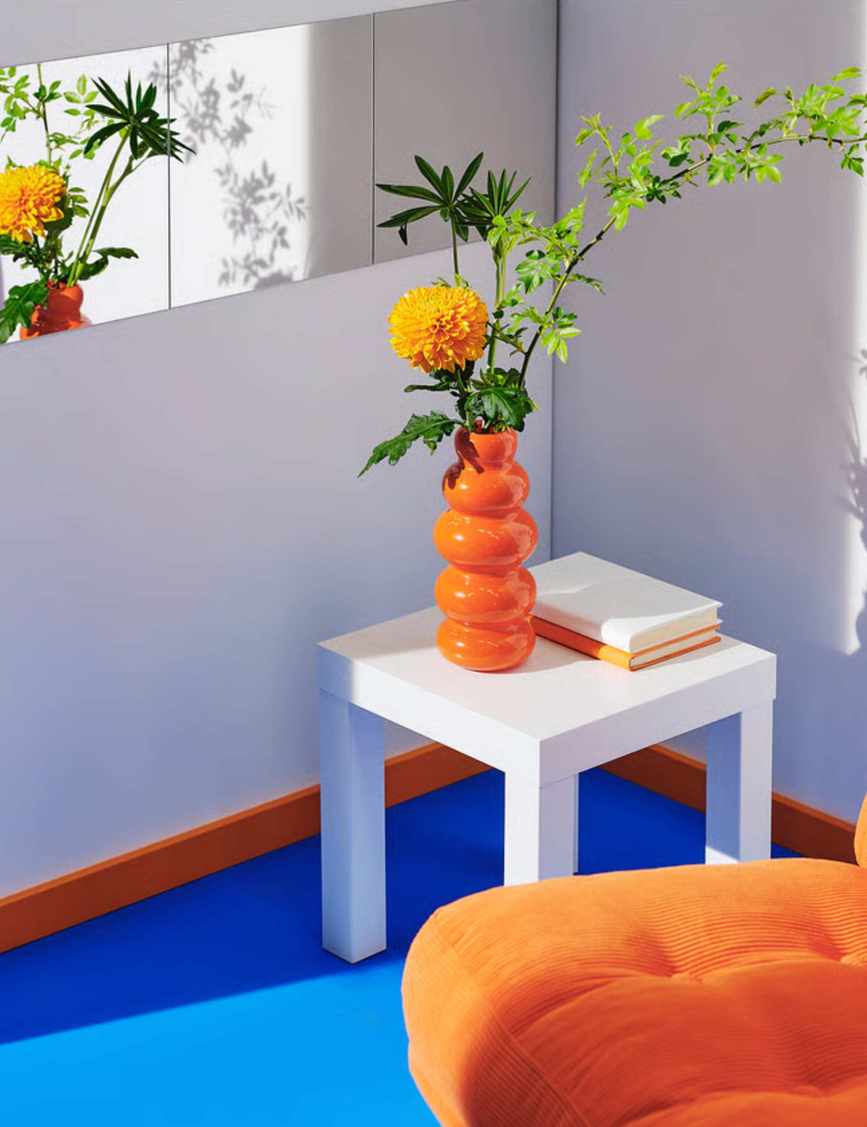 Orange vase and armchair on a cobalt blue rug