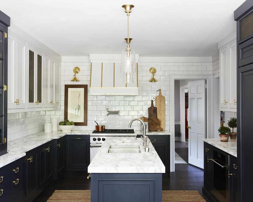 A kitchen with continuous white backsplash tiling and dark blue cabinets, showcasing full wall white kitchen backsplash inspirations.