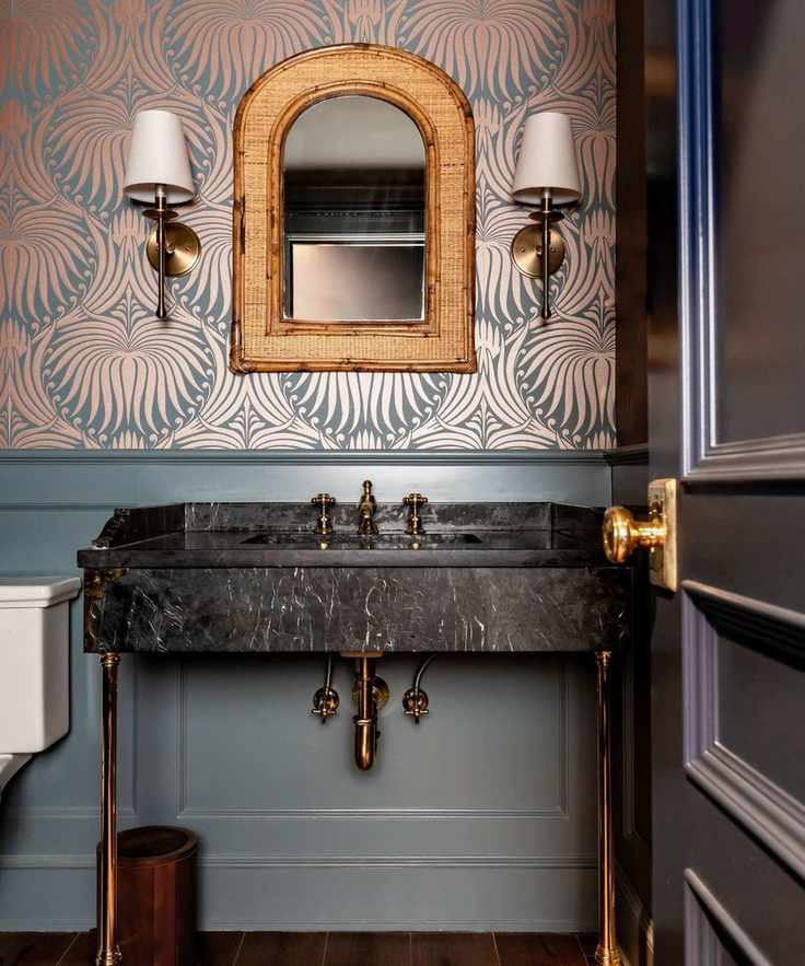 A stylish bathroom featuring a marble sink, gold fixtures, and teal wallpaper