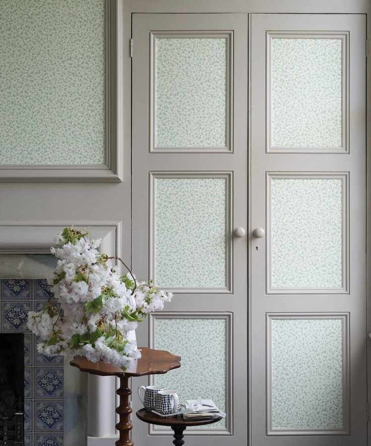 An example of how to hang wallpaper on gray cupboard doors, beside a traditional dove gray fireplace.