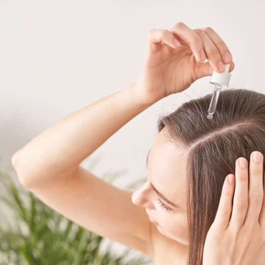 Woman Applying Topical Hair Care Product to Achieve Healthy Hair Woman Applying Topical Hair Care Product to Achieve Healthy Hair