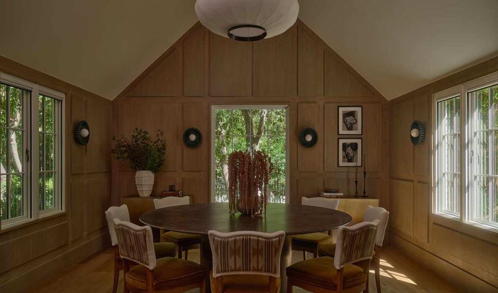 a wooden clad dining room with paneled walls and a vaulted ceiling with a large round table