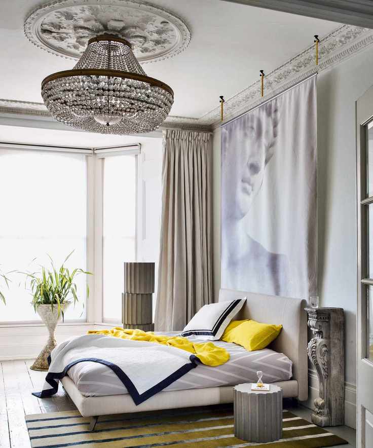 A bedroom showcasing a large empire chandelier with modern artwork