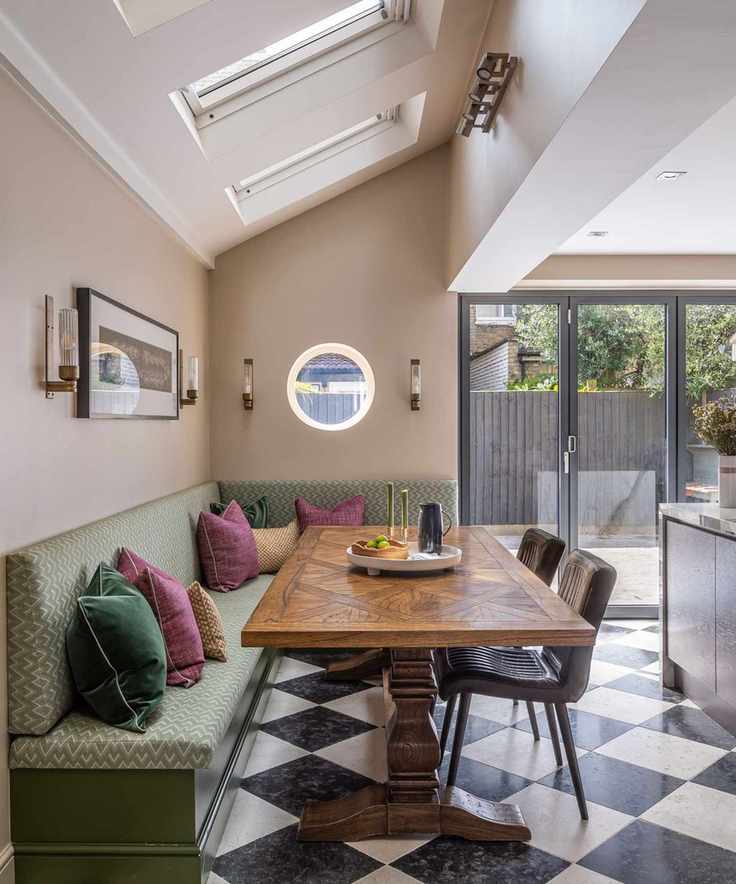 A modern kitchen with walls painted in Oxford Stone, featuring a green bench and bi-fold doors.