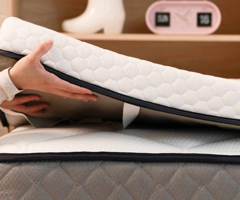 Mattress topper being laid on a bed