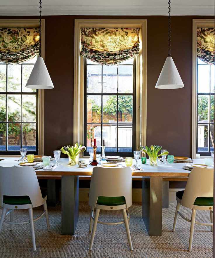 dining room with brown walls, swag botanical blinds, white pendants, white washed wooden table and white modern chairs