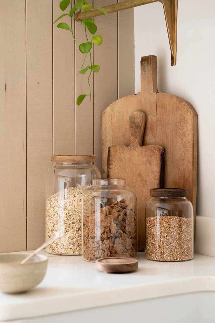 Glass containers and wooden cutting boards leaning in the corner of a kitchen