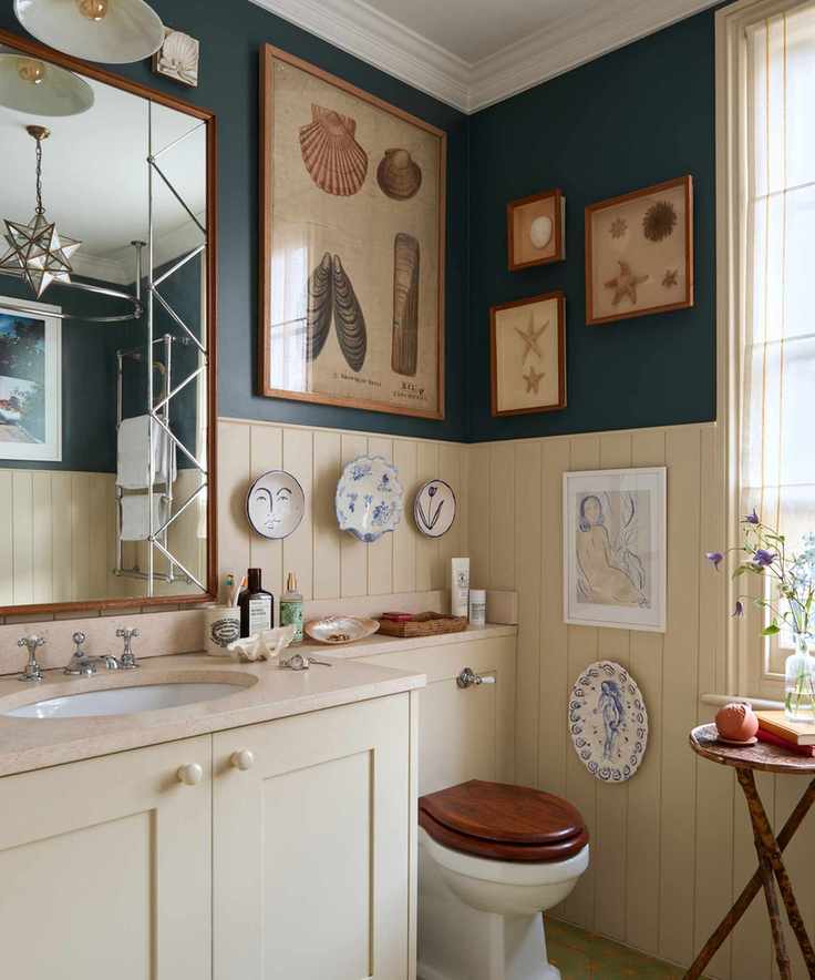 Cream wood panelled bathroom with vintage shell prints, ceramic plates on walls and large mirror