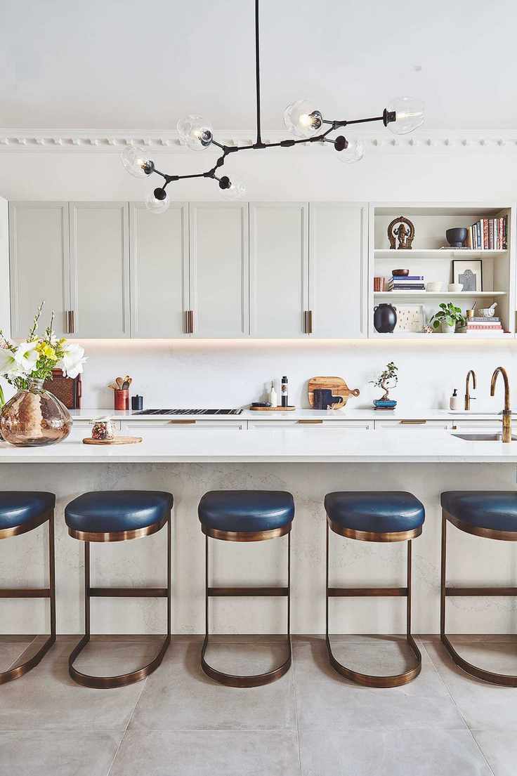 Black statement light in a white scheme with a row of blue and metal bar stools