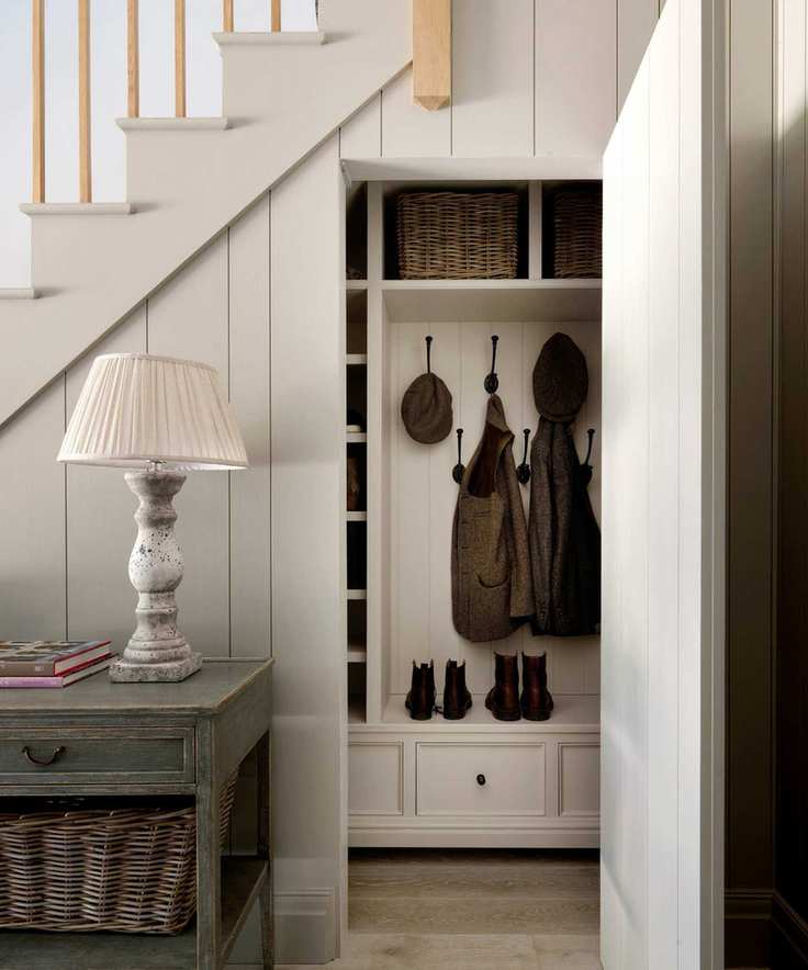white panelled painted staircase with a boot room hidden underneath behind a concealed door that opens up to boot and coat storage