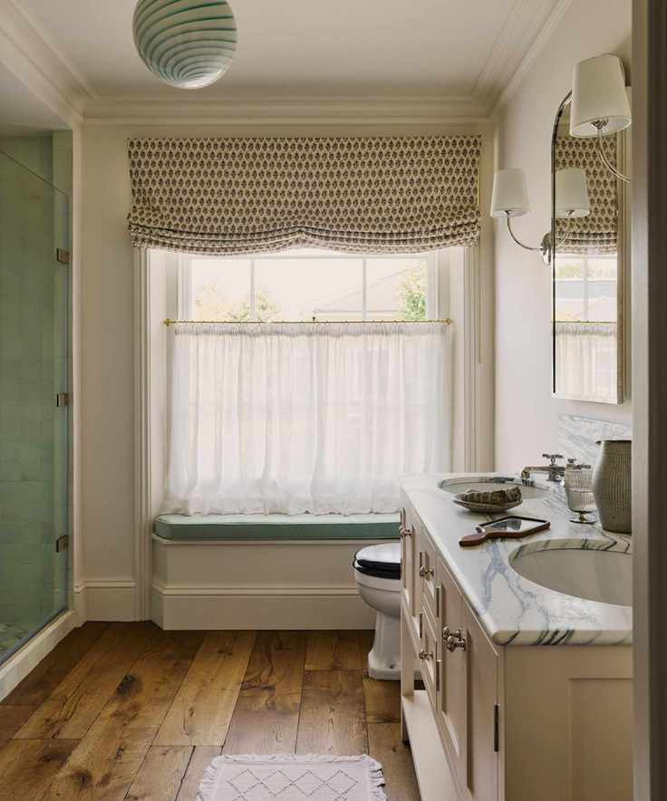 Bright bathroom with a blue window seat and sheer cafe curtains